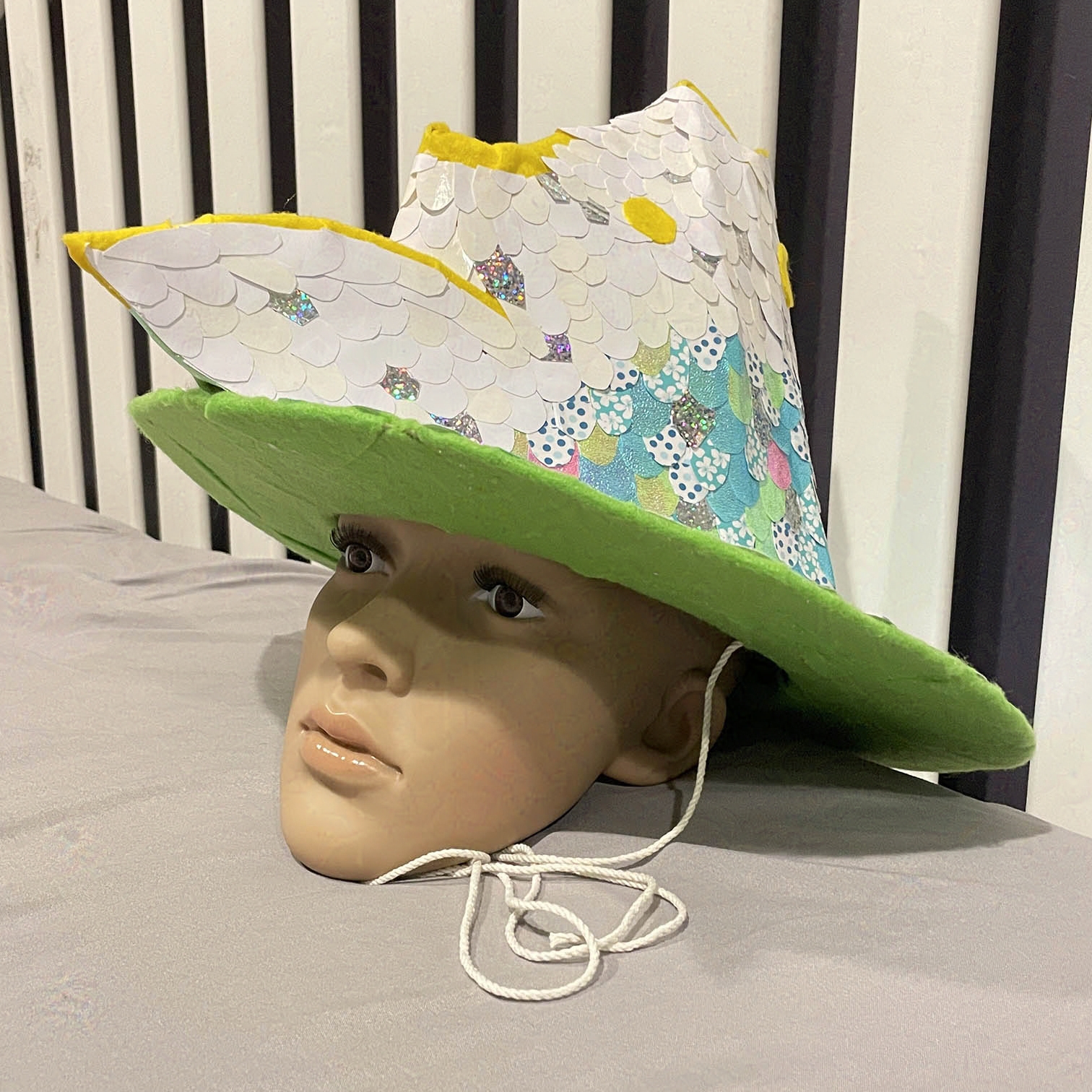 Witch hat with three fish heads on mannekin head.