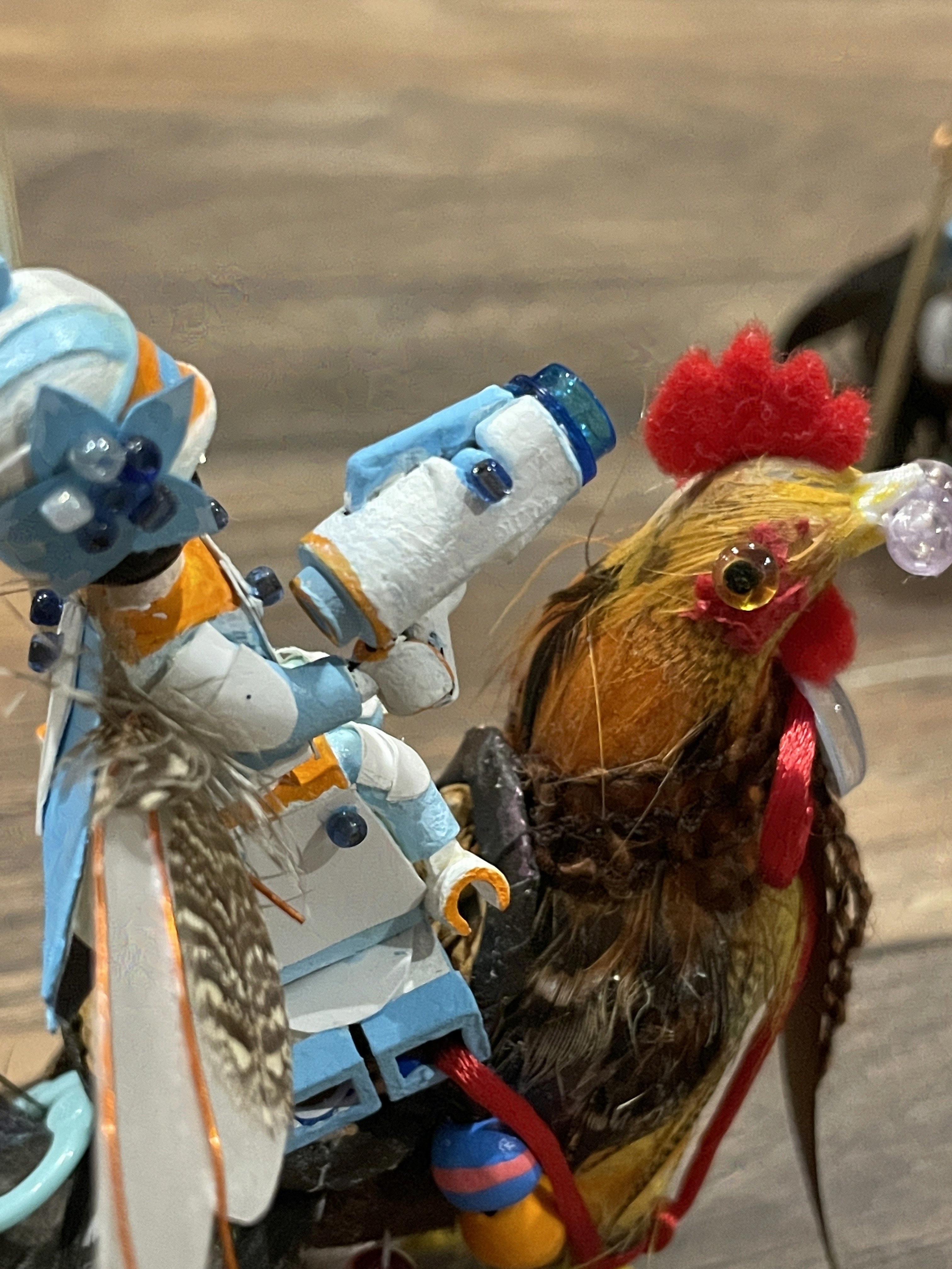 White and blue gun held by man. The man is secured to the chicken with a red ribbon threaded through the leg holes.